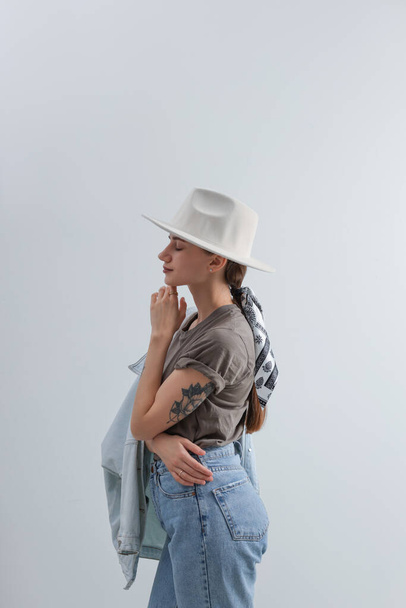 Young woman with hat and stylish bandana on light background - Foto, afbeelding