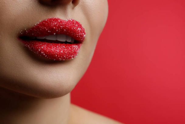 Closeup view of woman with lips covered in sugar on red background. Space for text - Fotografie, Obrázek