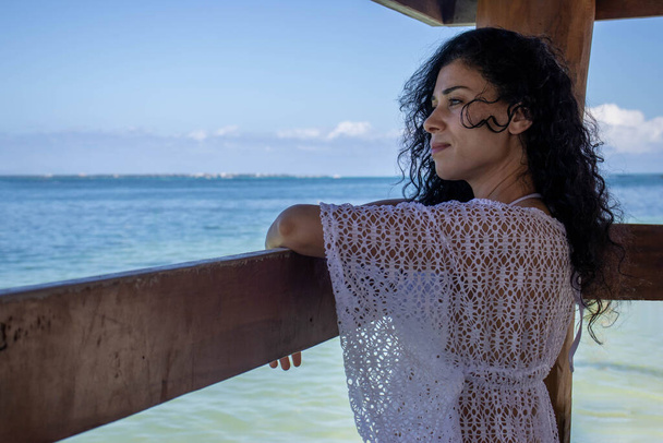 Junge sexy Frau, die von einem Pier aus die Schönheit des türkisfarbenen Karibischen Meeres bewundert und darüber nachdenkt, ist dies ein entspannter, romantischer und idealer Ort für Tourismus und Sommerurlaub. - Foto, Bild