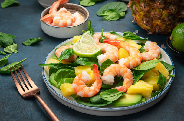 Pineapple salad with shrimps, spinach, avocado and lime on blue stone kitchen table, top view. Healthy eating, balanced, clean diet food, weight loss concept - Photo, image