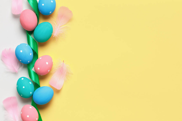 Easter composition on a yellow background. Colored eggs ribbon feathers. Top view flat lay border copy space - Foto, immagini