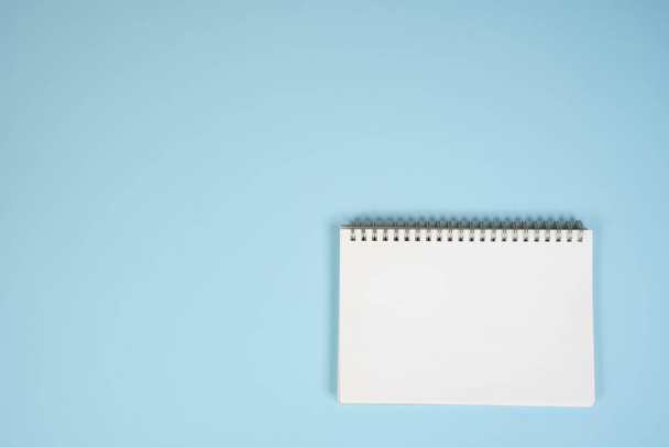 a blank white notepad on a blue surface - Zdjęcie, obraz
