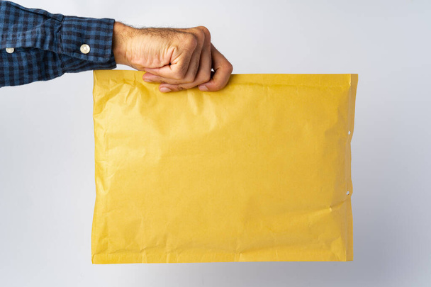Male hand holding parcel post against white background - Foto, Bild