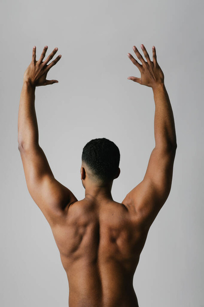Strong athletic fitness black man shows naked muscular body. Back view.  - Foto, imagen