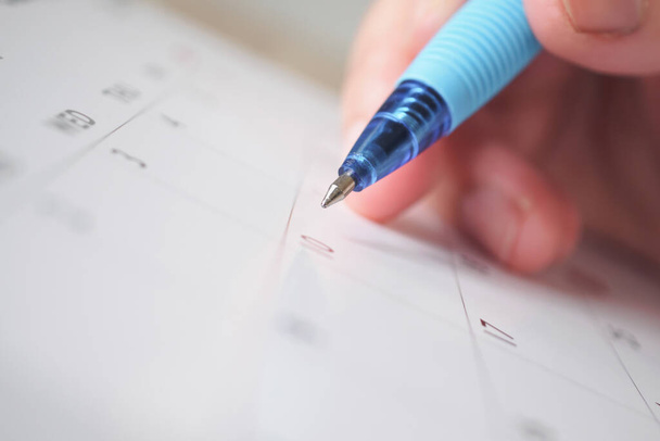 Vrouw hand met pen schrijven op kalender datum business planning afspraak vergadering concept - Foto, afbeelding