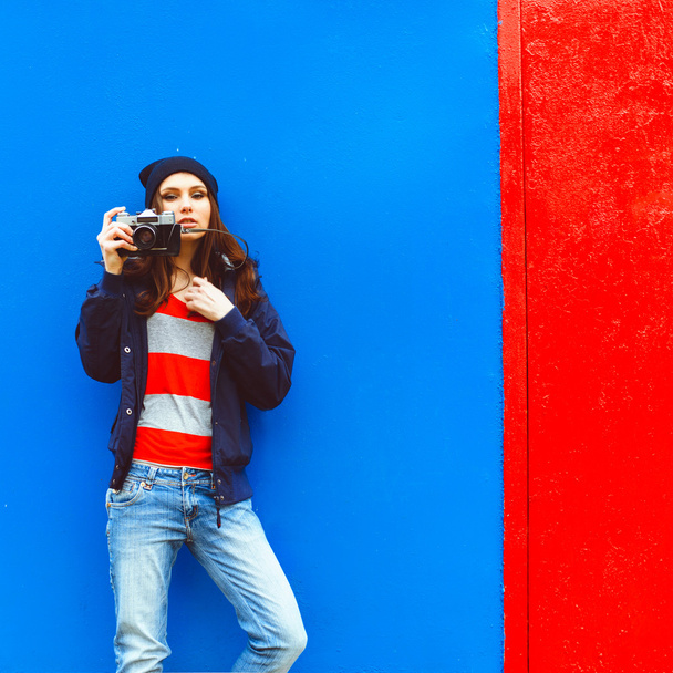 portrait of a beautiful hipster girl with a camera on the background photon makes blue walls and red doors - Foto, immagini