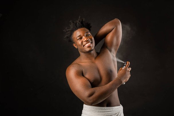 adult african man with athletic build with deodorant on black background - Photo, image