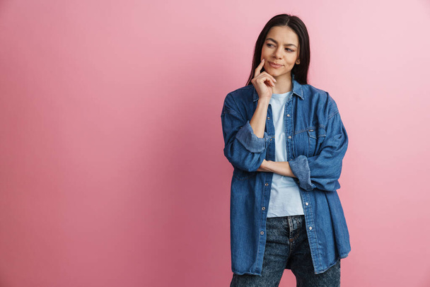 Young hispanic thinking woman posing and looking aside isolated over pink wall - Photo, image