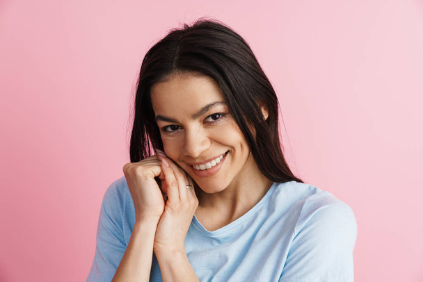 Brunette hispanic woman smiling and looking at camera isolated over pink wall - Photo, Image
