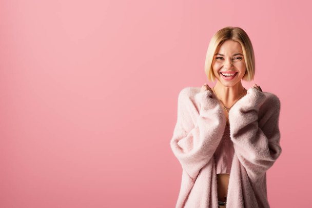 cheerful young woman in soft cardigan isolated on pink  - Zdjęcie, obraz