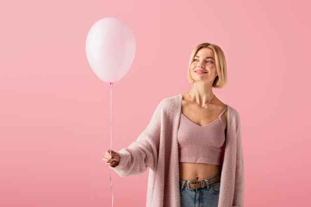 cheerful blonde woman in cardigan holding balloon isolated on pink - Foto, immagini