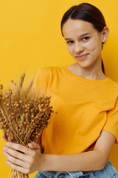 photo pretty girl fashion in yellow t-shirt dried flowers bouquet posing isolated background - Foto, imagen