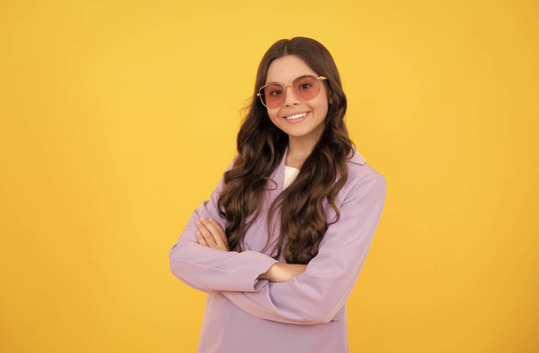 happy child with curly hair in stylish purple jacket and sunglasses on yellow background, happiness. - Photo, Image