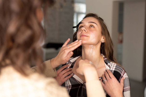 Make-up artist applica la base di make-up sul viso della ragazza. Foto di alta qualità - Foto, immagini