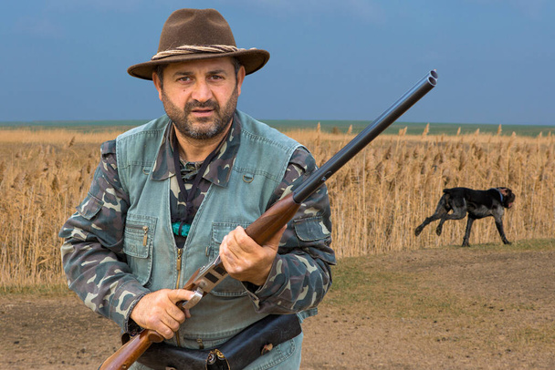 Hunter man in camouflage met een pistool tijdens de jacht op zoek naar wilde vogels of wild. Herfst jachtseizoen. - Foto, afbeelding