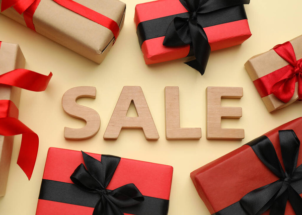 Word Sale made of wooden letters and gift boxes on beige background, flat lay - 写真・画像