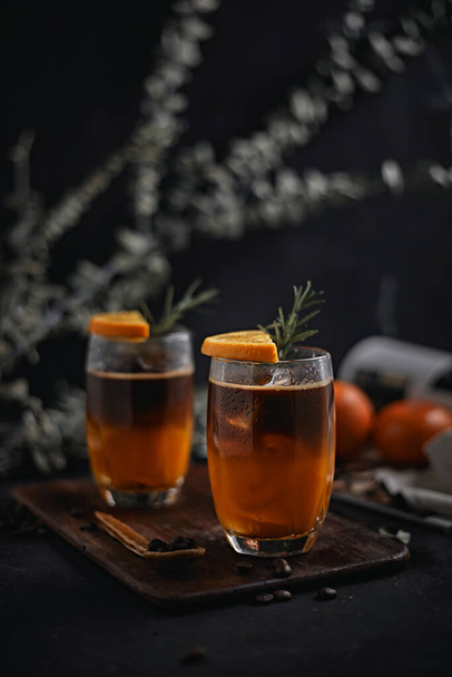 A glass of iced americano black coffee and layer of orange  - Фото, изображение