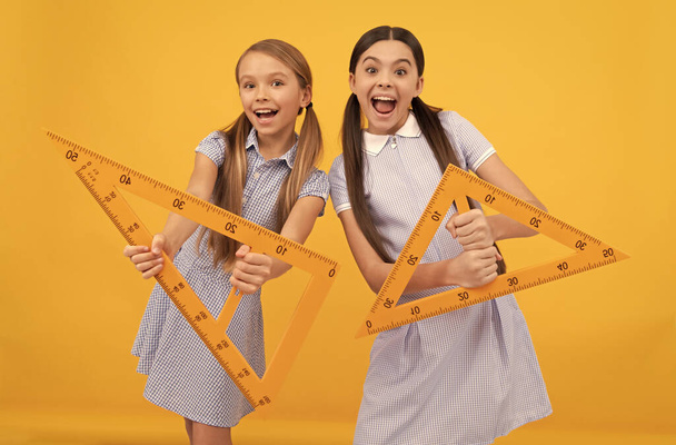 Saiba quais são os ângulos. Meninas adolescentes felizes segurar réguas triangulares. Lição de geometria. Preparando lição - Foto, Imagem