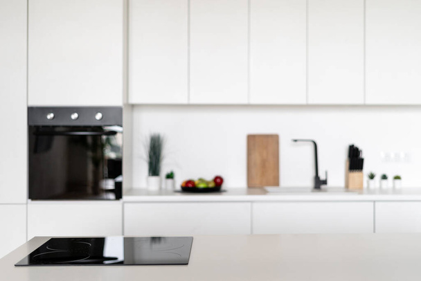 Projeto de interiores de cozinha estilo nórdico com fogão de indução preto. Utensílios de cozinha modernos e decoração no fundo. Conceito de conforto doméstico. Apartamento espaçoso e luminoso - Foto, Imagem