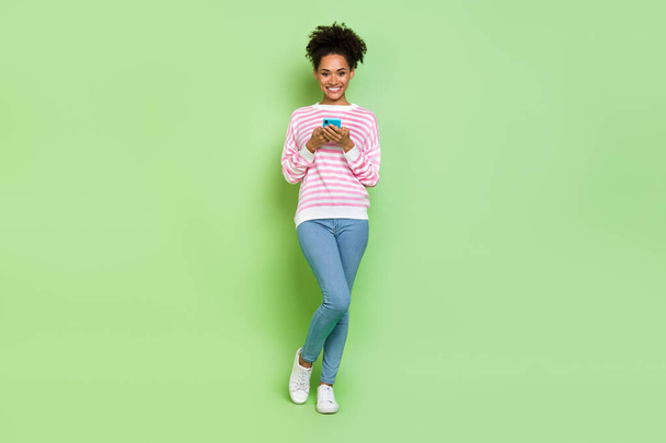 Photo of pretty shiny lady dressed pink pullover typing modern device isolated green color background - Фото, зображення