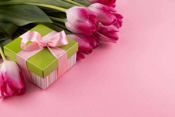 Blurred image of a gift box, pink tulips on a pink background with space for writing text.Gift card. - Foto, Imagem