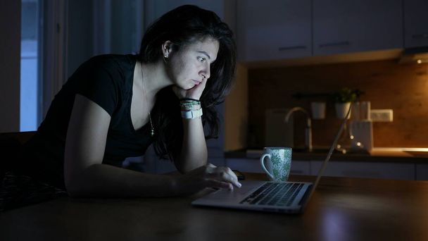 Frau spätabends vor Laptop auf Küchenbalkon - Foto, Bild