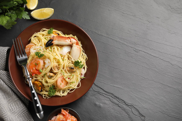 Delicious pasta with sea food served on black table, flat lay. Space for text - Photo, Image