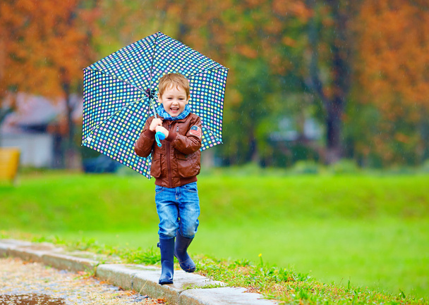 happy boy running under an autumn rain - Фото, изображение