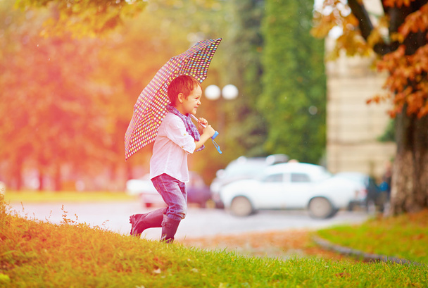 cute boy enjoying an autumn rain in city park - Foto, Imagen