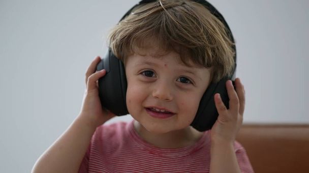 Toddler boy using headphones trying to put but then removing headphones - Photo, Image