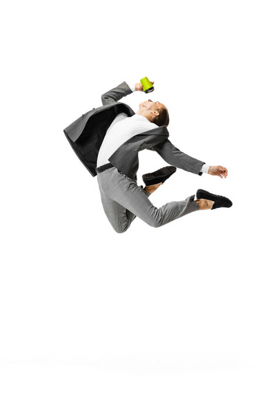 One young man in gray business suit jumping, flying isolated on white background. Business, art, motion, action, creativity, inspiration concept. - Photo, image