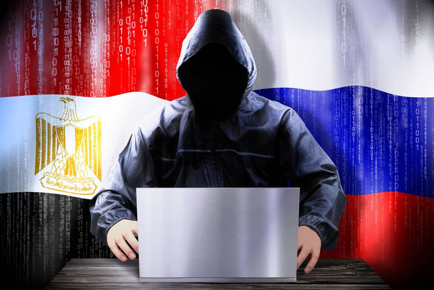 Ανώνυμος χάκερ που δουλεύει σε ένα λάπτοπ, σημαίες της Αιγύπτου και της Ρωσίας - Φωτογραφία, εικόνα