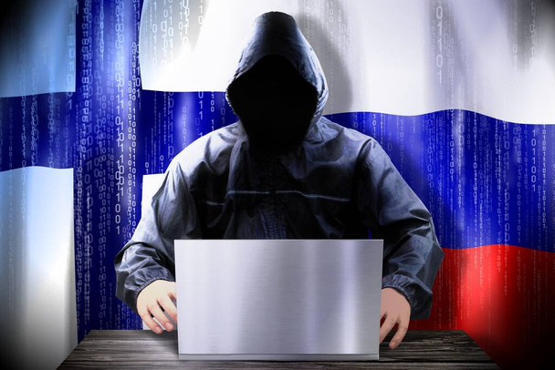 Anonieme hacker werkt aan een laptop, vlaggen van Finland en Rusland - Foto, afbeelding