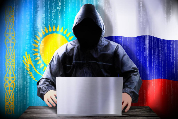 Nimetön hakkeri työskentelee kannettavan tietokoneen, liput Kazakstanin ja Venäjän - Valokuva, kuva