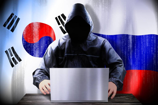 Anonyme Hacker arbeiten an einem Laptop, Flaggen von Südkorea und Russland - Foto, Bild