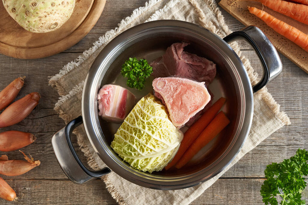 Huesos de médula, carne de res y verduras frescas en una olla de agua - ingredientes para preparar caldo o sopa casera - Foto, imagen