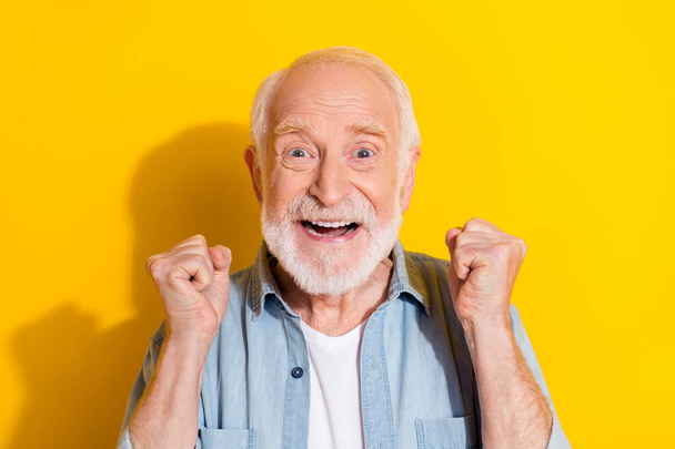 Portrait of attractive lucky cheerful grey-haired man rejoicing great success isolated over bright yellow color background - Fotó, kép