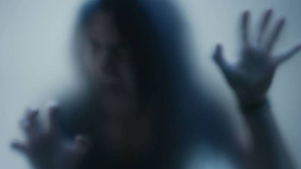 Person in pain behind glass woman suffering from depression concept feeling trapped defocused shot - Photo, Image