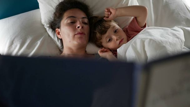 Parent reading a bedtime story to child in bed - Photo, Image