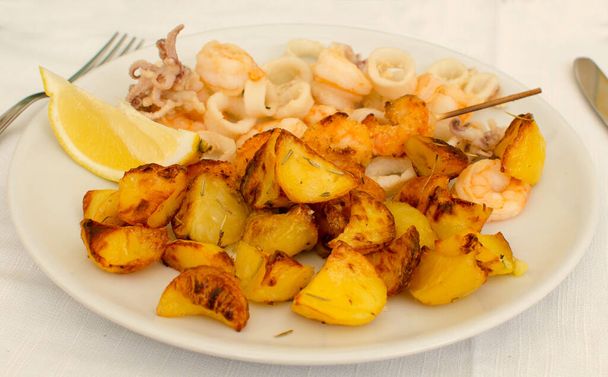 Az étel Fritto con spiedino e patate - Az étel a burgonya és tenger gyümölcsei sült. Spiedino és Lemon. Olasz élelmiszer - Fotó, kép