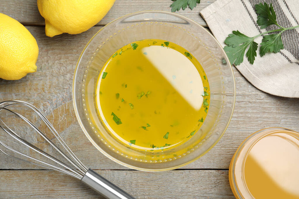 Bowl with lemon sauce and ingredients on wooden table, flat lay. Delicious salad dressing - Zdjęcie, obraz
