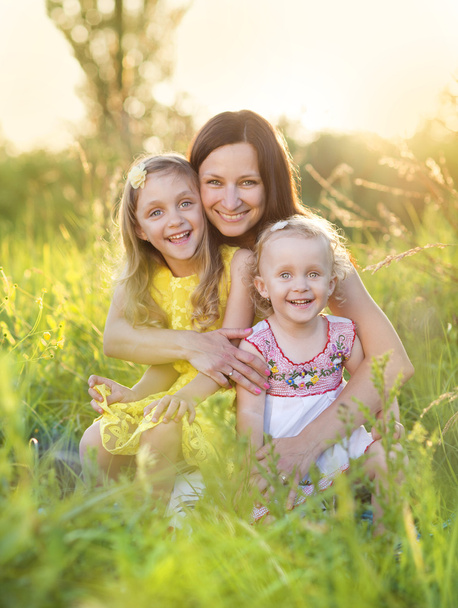 Happy mother with daughters in sunny meadow - Φωτογραφία, εικόνα