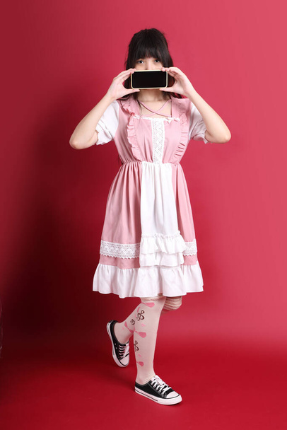 The teen Asian girl with cute Japanese costume standing on the red background. - Fotó, kép