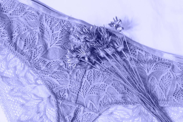 Sexy Damenunterwäsche und Blumen auf dem Bett. Sehr peri-violette BH, Spitzenunterwäsche auf weißem Hintergrund. Beauty-Blog-Konzept. Draufsicht, flache Lage - Foto, Bild