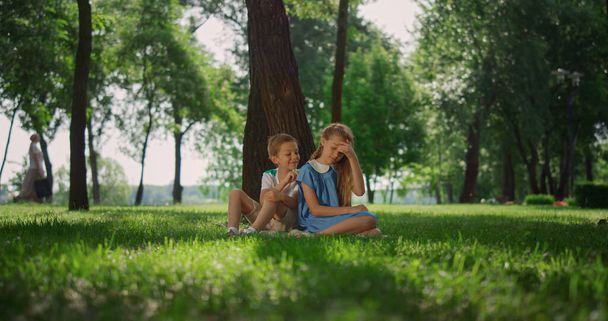 Χαρούμενα παιδιά που παίζουν κάτω από το δέντρο. Χαμογελώντας παιδιά διασκεδάζουν έξω το Σαββατοκύριακο. - Φωτογραφία, εικόνα