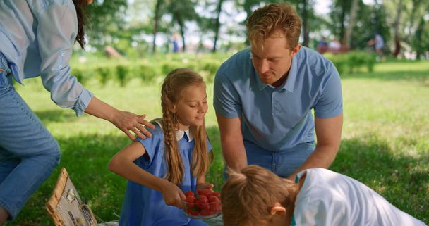Happy family preparing picnic in park. Active summer rest on fresh air concept. - Photo, Image