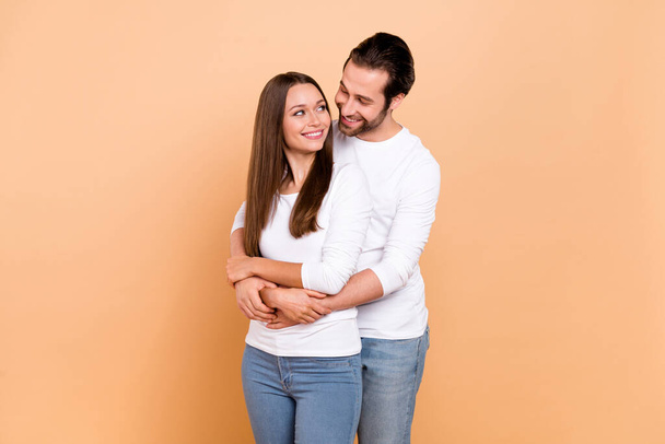 Photo of optimistic millennial brown hairdo couple hug look wear white outfit isolated on beige color background - Zdjęcie, obraz