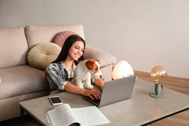Portrait of young beautiful hipster woman working on a laptop with her adorable wire haired Jack Russel terrier puppy at home. Female with rough coated pup. Interior background, close up, copy space. - Fotografie, Obrázek