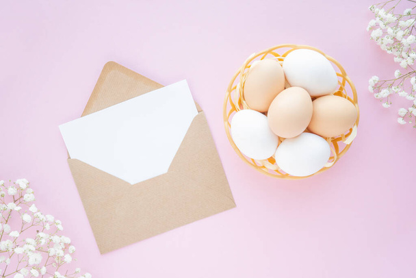Felices huevos naturales de Pascua en nido, sobre artesanal y decoración de flores sobre fondo rosa. plano, maqueta, lugar para el texto - Foto, imagen