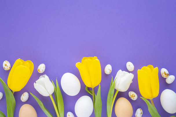 Composición pascual de tulipanes y huevos de Pascua sobre fondo púrpura con espacio para copiar. Piso tendido, vista superior - Foto, imagen